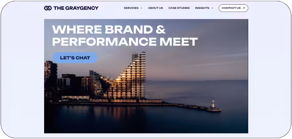 The Graygency website homepage showcasing its expertise in paid social marketing with the tagline 'Where Brand & Performance Meet' and a modern waterfront building in the background.
