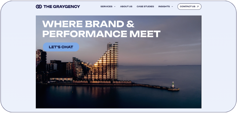 The Graygency website homepage showcasing its expertise in paid social marketing with the tagline 'Where Brand & Performance Meet' and a modern waterfront building in the background.
