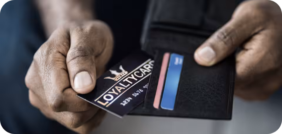 Close-up of a person holding a wallet and pulling out a loyalty card, representing customer rewards programs, loyalty benefits, and consumer engagement.