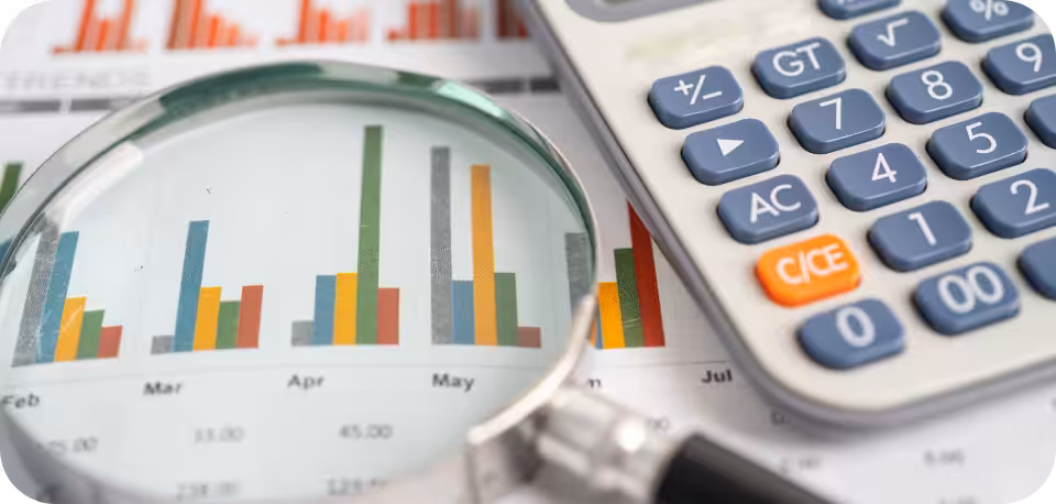 A close-up view of financial charts and graphs with a magnifying glass and a calculator, symbolising data analysis, financial planning, and business strategy.