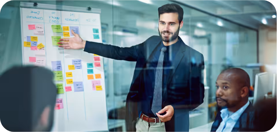 Business professional in a suit presenting a strategy on a white board with colourful sticky notes during a team meeting, symbolising effective planning and collaboration in TikTok remarketing versus retargeting