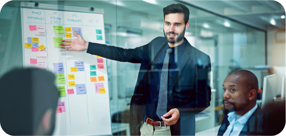 Business professional in a suit presenting a strategy on a white board with colourful sticky notes during a team meeting, symbolising effective planning and collaboration in TikTok remarketing versus retargeting